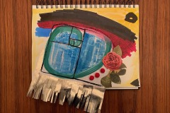 Zachary and Annie Burkes. A photograph of a painting in a spiral bound sketchbook against a wooden surface. A Fibonacci spiral in blue and green is in the centre against a backdrop of yellow with an arc in brown, red and blue. Paper cut into fringes extrudes from the page. Three red balls and a pink rose with leaves are collaged to the right of the spiral.